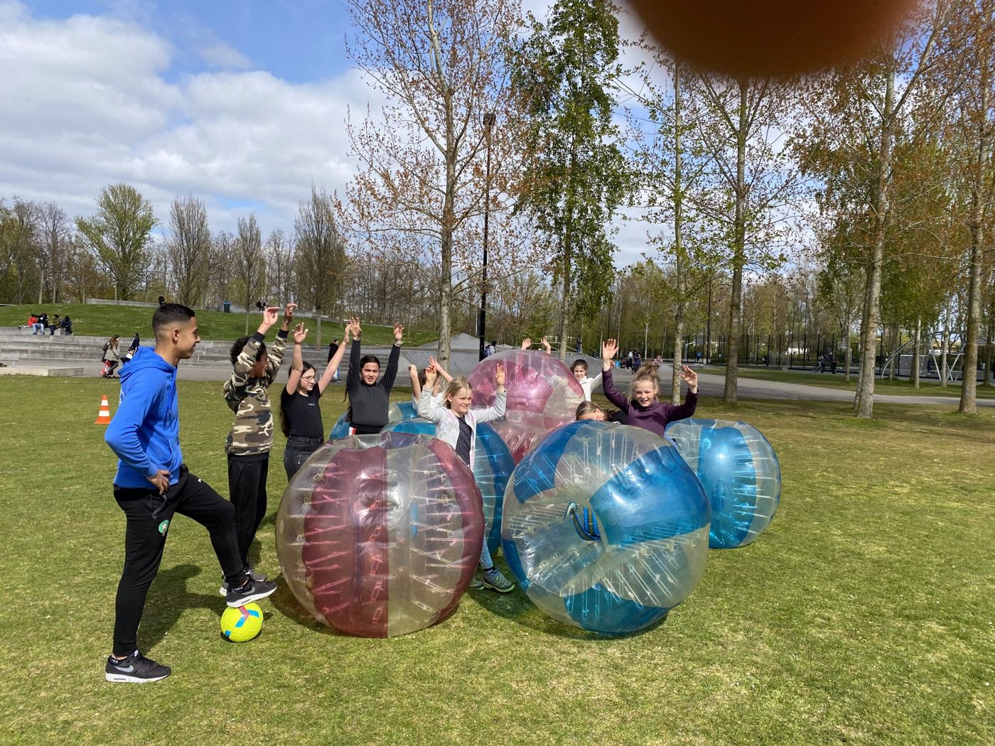 Jongeren doen bubbelvoetbal op het grasveld