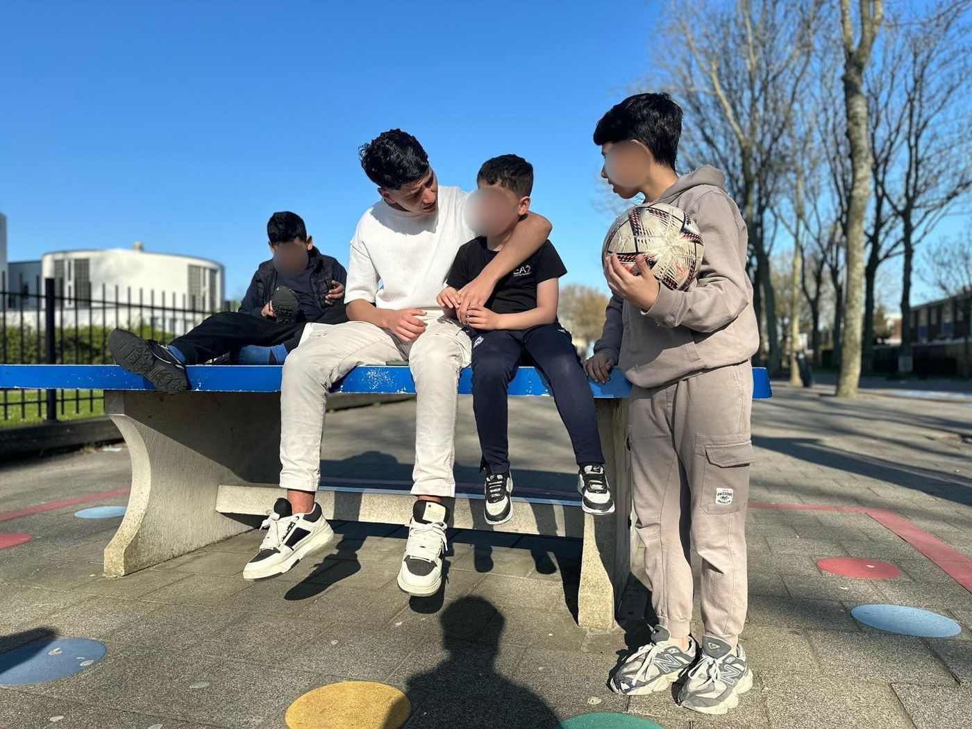 Een groep jongeren zit samen op een tafeltennistafel buiten