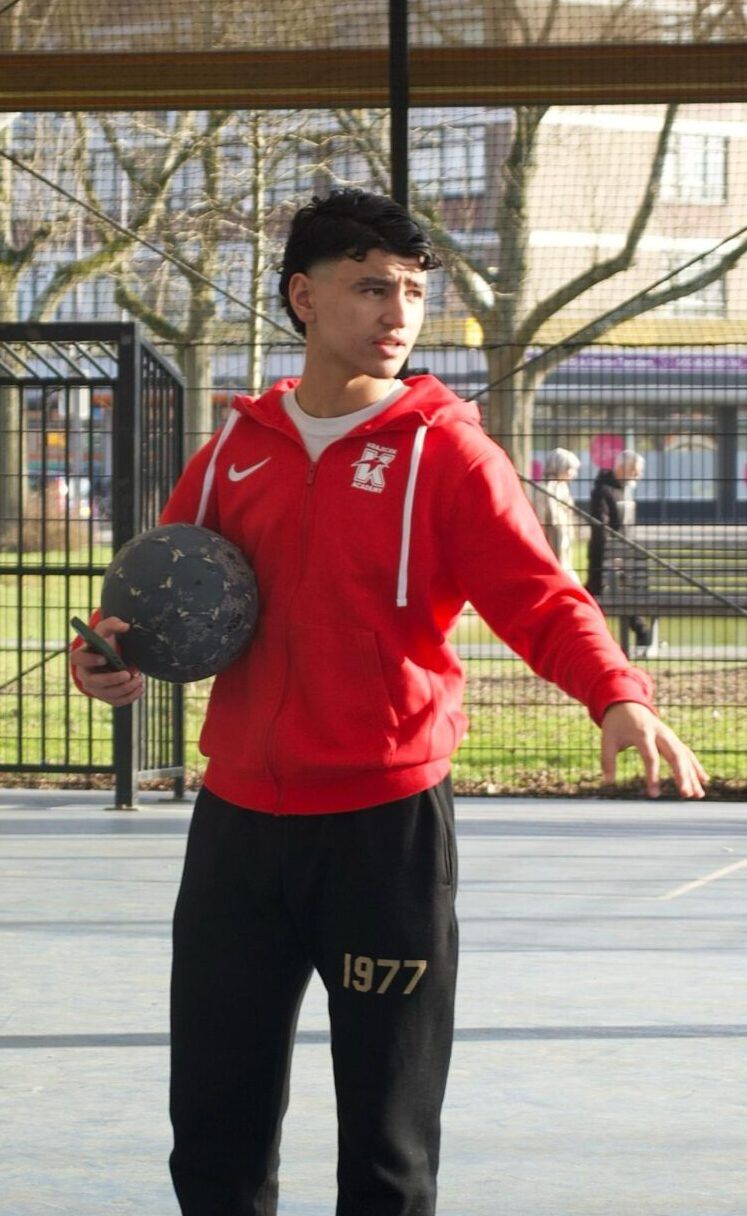 Jongere met een basketbal op een sportveld
